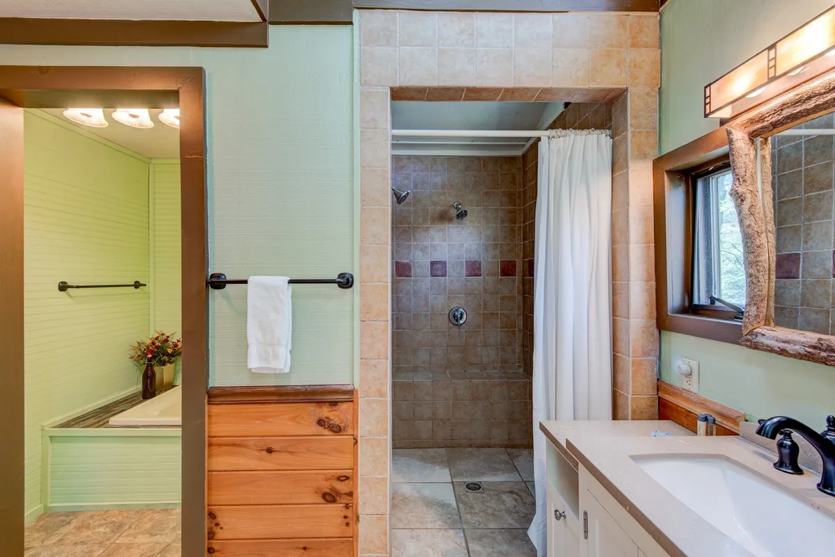 A calming bathroom space with a modern vanity, shower area, bathtub nook, and natural light streaming through a window. The overall atmosphere is serene, ideal for relaxation and self-care routines.