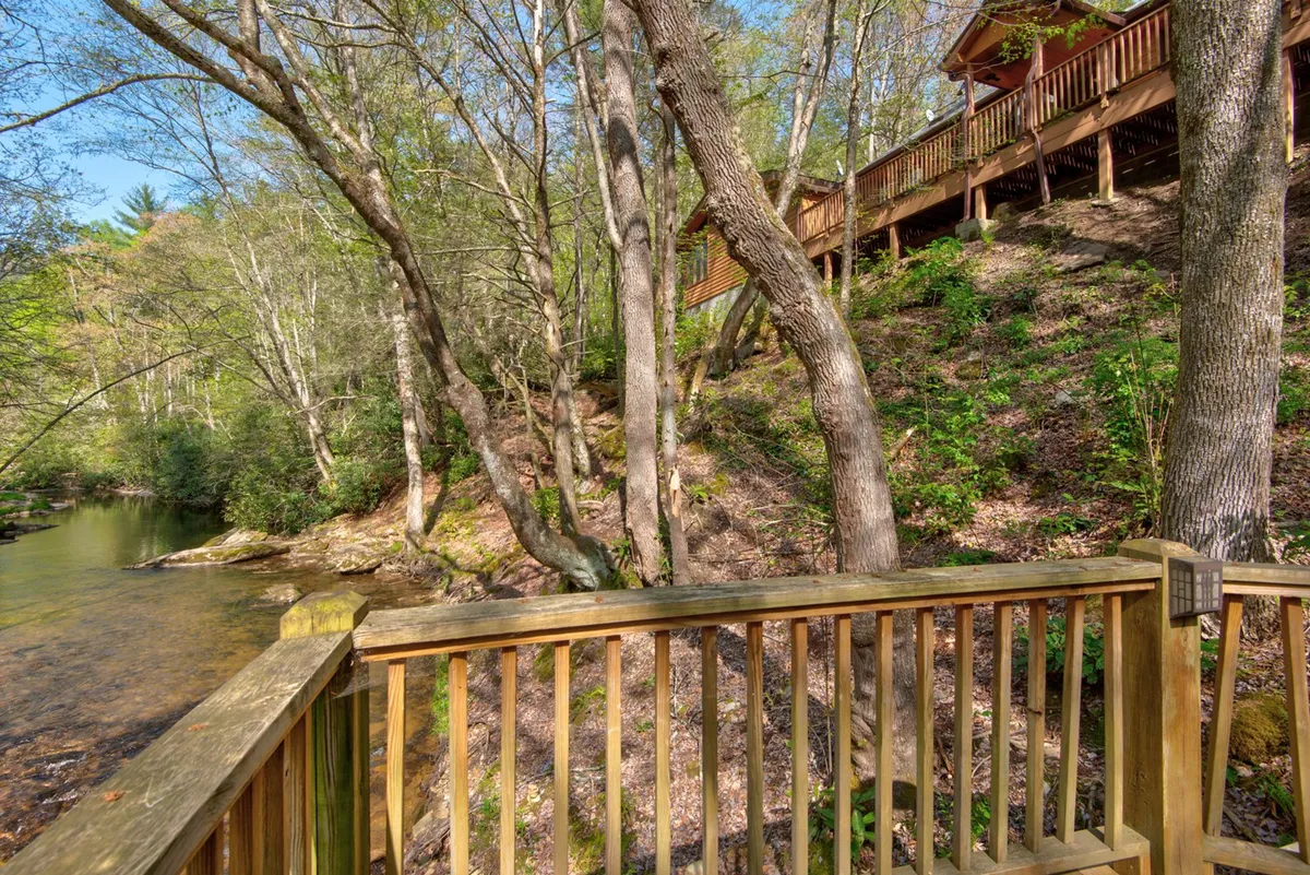 An elevated wooden deck with a sturdy railing overlooks a beautiful river and lush trees. The vantage point provides sweeping views of the water below, inviting activities like birdwatching or simply soaking in the peaceful natural surroundings.