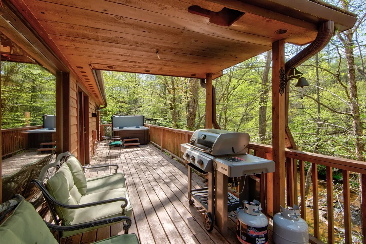 A wooden deck with an outdoor seating area and a grill, nestled amidst greenery. The relaxed setup is ideal for barbecues, casual gatherings, and enjoying the fresh mountain air, symbolizing the balance of adventure and comfort described in the section.